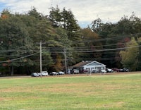 a field with trees and a house in the background
