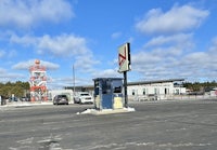a gas station with a sign in the middle of the road