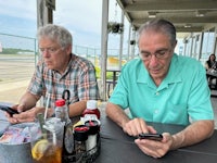 two men sitting at a table looking at their cell phones